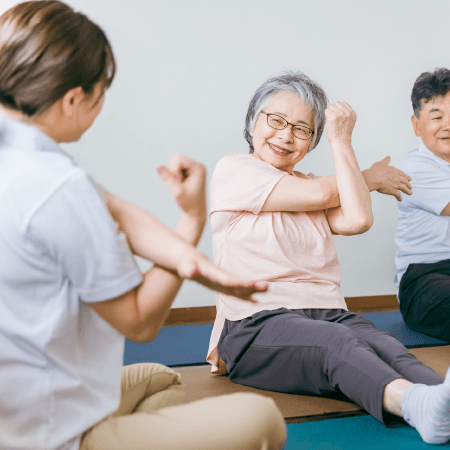 専門家の指導のもとストレッチをする高齢夫婦