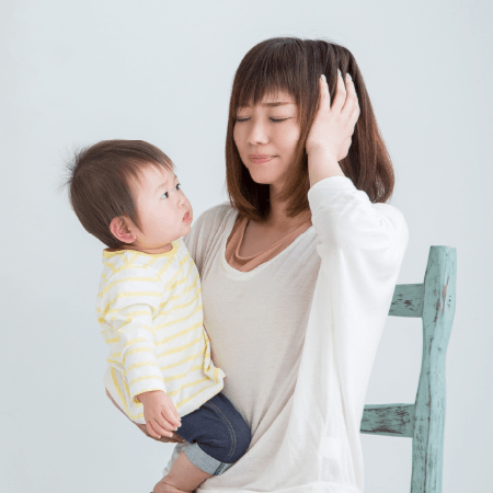 子供を抱っこしながら頭を抱えるお母さん